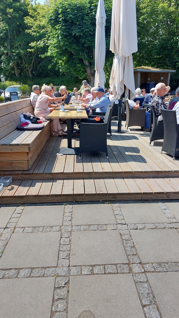 Gæsterne hygger og drikker kaffe på terrassen i det fine solskinsvejr.